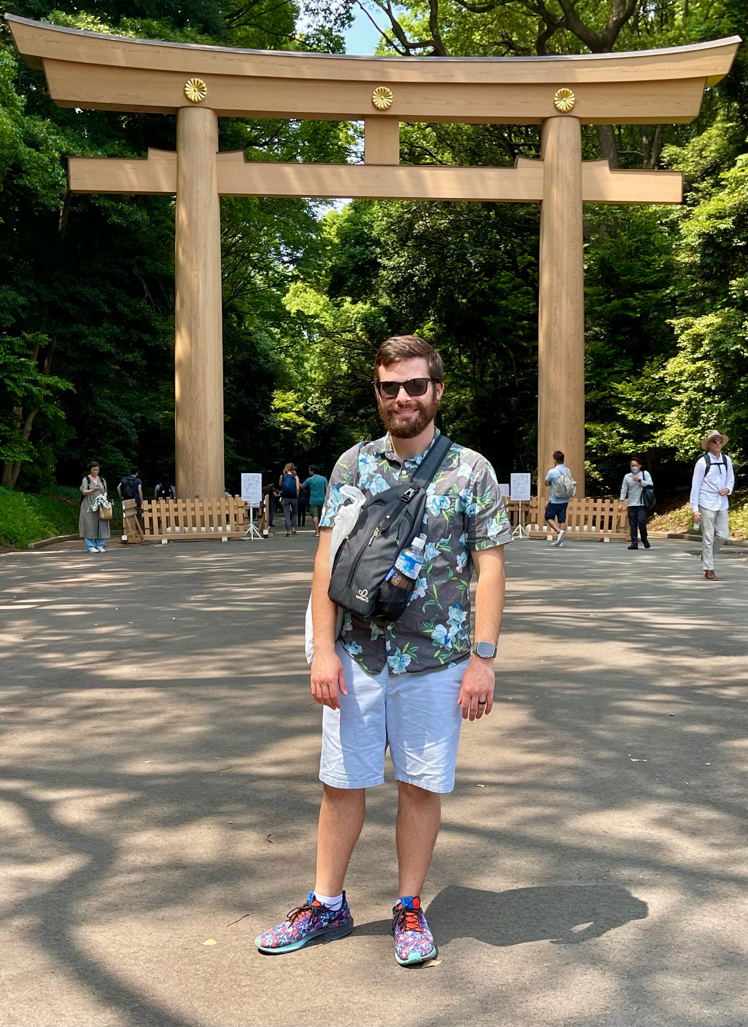 Andrew in front of a wooden torii gate at Meiji Jingu, Tokyo